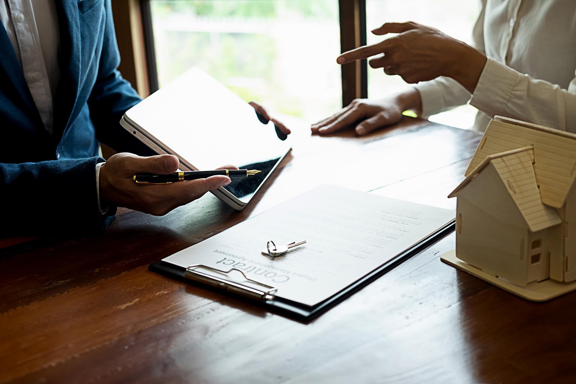 Consultant imobiliar la întâlnire cu clientul, documente pe masă
